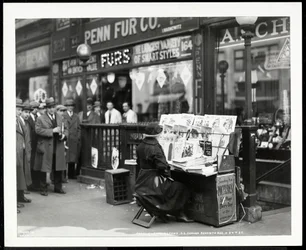Marchand de journaux aveugle, Aaron Weintraub, à son stand au coin sud-est de la 7e Avenue et de la 32e Rue, New York, 1926